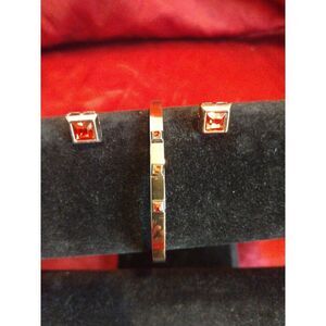 Gold tone bangle bracelet and matching earrings with simulated garnet accents